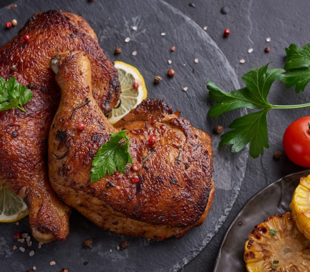 grilled-chicken-legs-barbecue-sauce-with-pepper-seeds-parsley-salt-black-stone-plate-black-stone-table